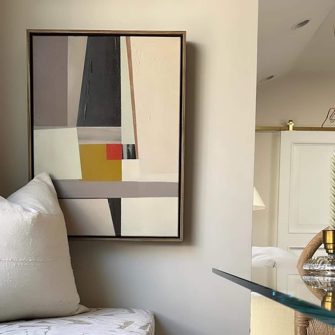 Abstract geometric painting with gray and warm colored rectangles in dark float frame hung in living room